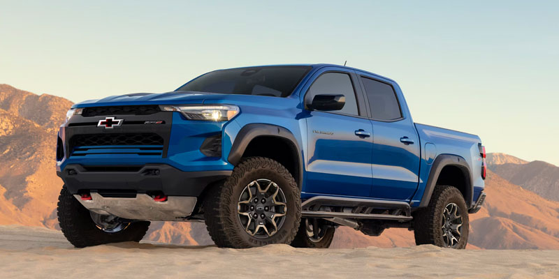 2026 Chevrolet Colorado blue pickup truck parked, shown in front-side profile, highlighting its bold stance, rugged design, and modern styling.