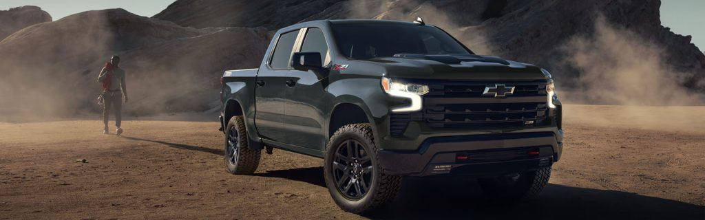 A dark green Chevrolet Silverado Z71 truck in a desert landscape with a person walking in the background.