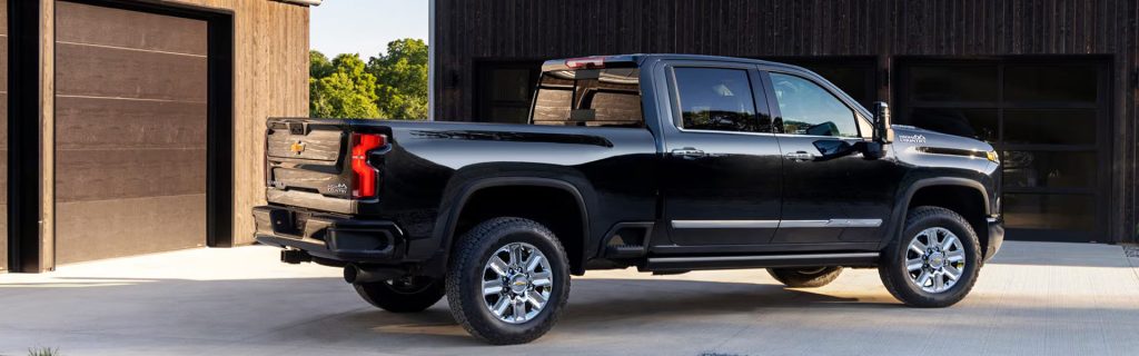 A black Chevrolet Silverado High Country truck parked in front of a wooden building.