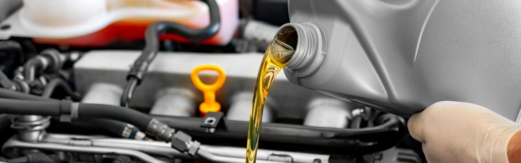 A person pouring engine oil into a car engine.